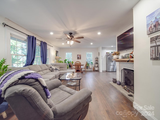 living room with dark hardwood / wood-style floors, a tile fireplace, and ceiling fan