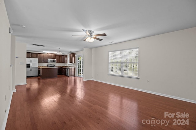 unfurnished living room featuring ceiling fan and dark hardwood / wood-style flooring