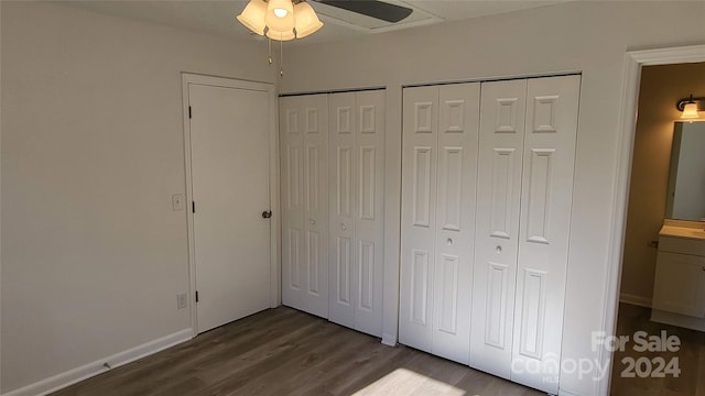 unfurnished bedroom featuring ceiling fan, multiple closets, and dark wood-type flooring