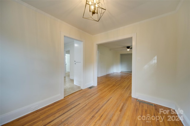 empty room with ceiling fan with notable chandelier, crown molding, and light hardwood / wood-style floors