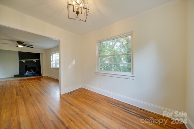 unfurnished living room with ornamental molding, a fireplace, hardwood / wood-style floors, and a wealth of natural light