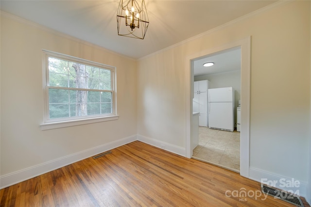 unfurnished room with crown molding, hardwood / wood-style floors, and a chandelier