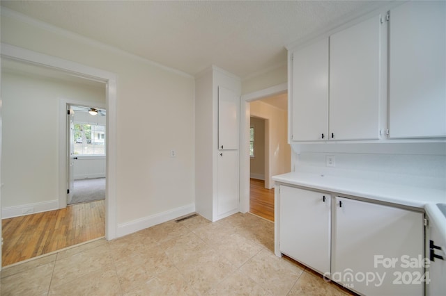 kitchen with ornamental molding, light hardwood / wood-style flooring, and white cabinets