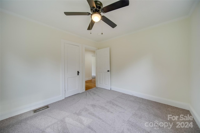 empty room featuring light carpet, ornamental molding, and ceiling fan