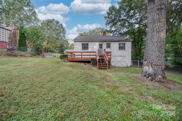 rear view of property with a wooden deck and a lawn