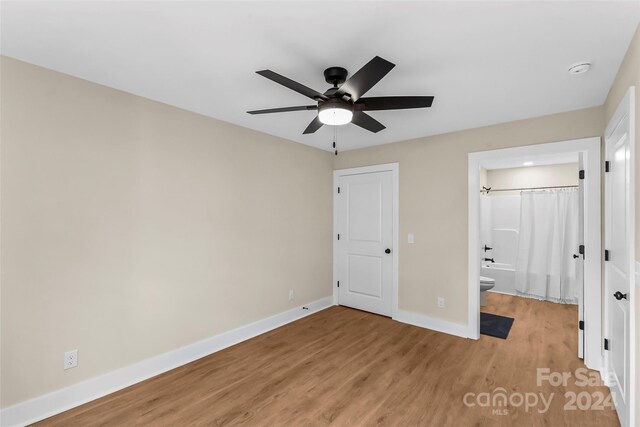 unfurnished bedroom featuring light wood-type flooring, ceiling fan, and connected bathroom