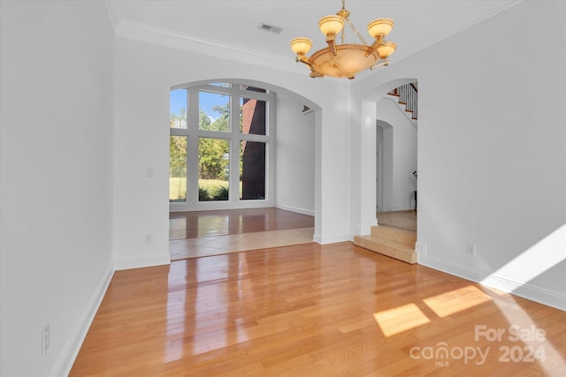 unfurnished dining area with crown molding, hardwood / wood-style floors, and a chandelier