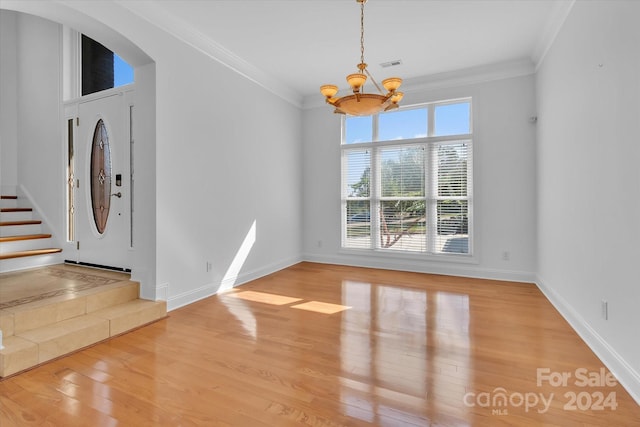 foyer entrance with light wood-type flooring, a chandelier, and ornamental molding