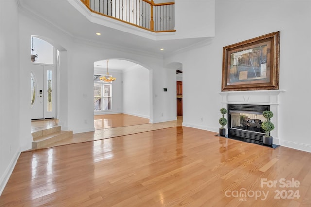 unfurnished living room featuring a high ceiling, hardwood / wood-style flooring, and crown molding