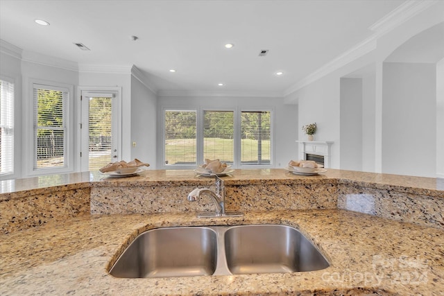 kitchen featuring light stone counters, crown molding, and sink