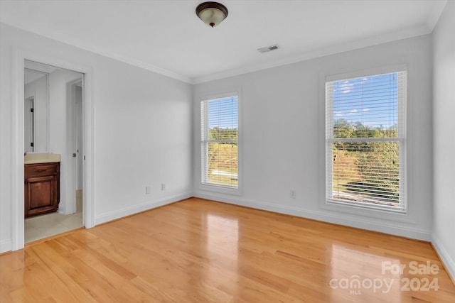 empty room featuring light hardwood / wood-style flooring, crown molding, and a healthy amount of sunlight