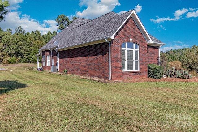 view of side of home featuring central AC unit and a yard