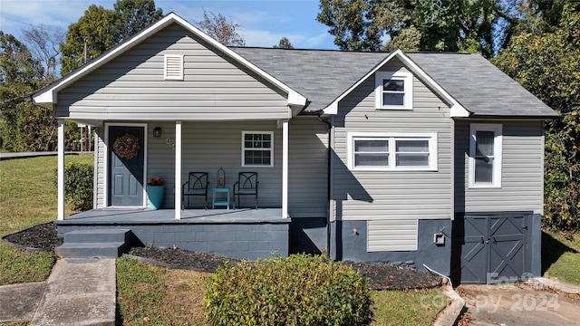 bungalow-style house featuring covered porch and a front lawn