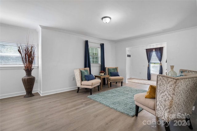 living area with light hardwood / wood-style flooring and ornamental molding