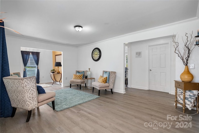 living area with ornamental molding and hardwood / wood-style floors