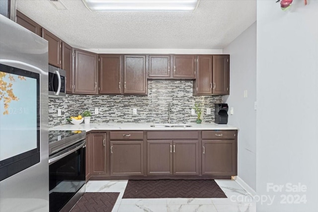 kitchen with appliances with stainless steel finishes, dark brown cabinets, decorative backsplash, and sink