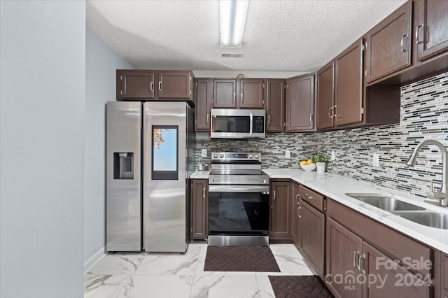 kitchen with dark brown cabinetry, sink, tasteful backsplash, a textured ceiling, and stainless steel appliances