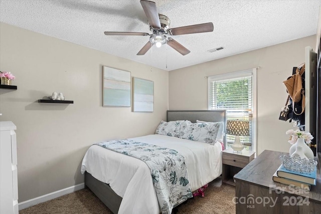 bedroom with dark colored carpet, ceiling fan, and a textured ceiling