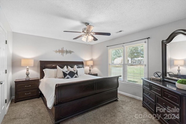 bedroom with ceiling fan, light colored carpet, and a textured ceiling