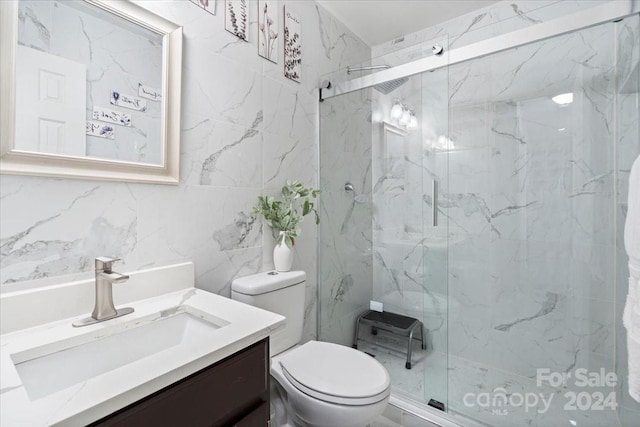 bathroom with vanity, tile walls, toilet, and a shower with door