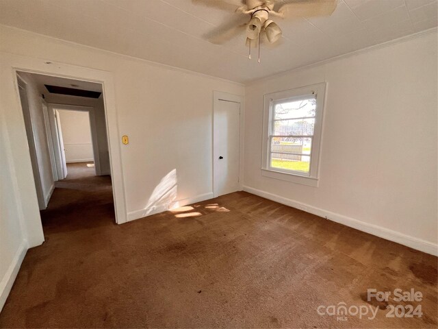 unfurnished bedroom featuring ornamental molding, dark colored carpet, and ceiling fan