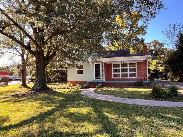 704 Mcadenville Rd, Lowell, NC 28098 - view of front of home with a chimney, a front yard, and brick siding