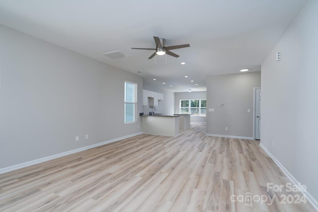 unfurnished living room featuring ceiling fan, sink, and light hardwood / wood-style floors