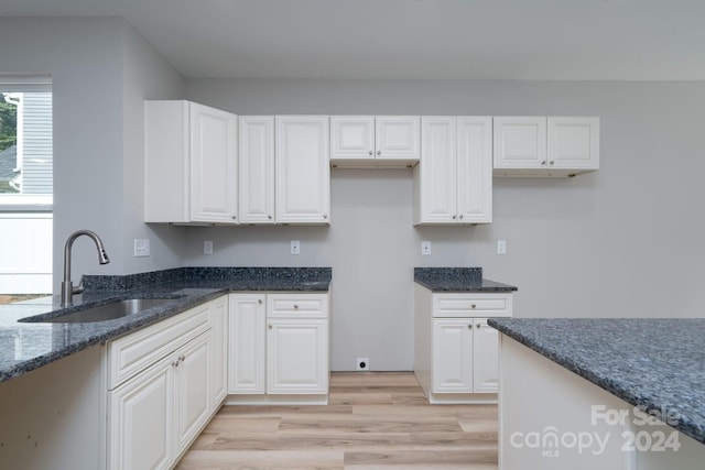 kitchen featuring dark stone countertops, sink, and white cabinetry