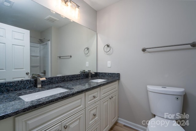 bathroom featuring a shower, hardwood / wood-style floors, vanity, and toilet