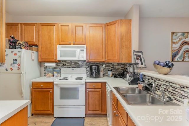 kitchen featuring backsplash, light hardwood / wood-style floors, white appliances, and sink