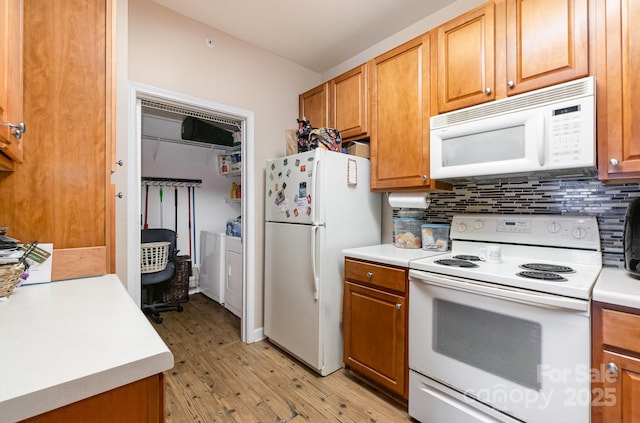 kitchen featuring white appliances, separate washer and dryer, and backsplash