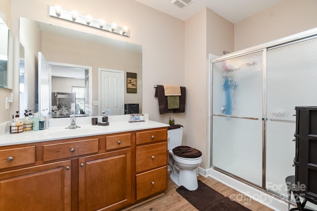 bathroom with wood-type flooring, vanity, toilet, and walk in shower