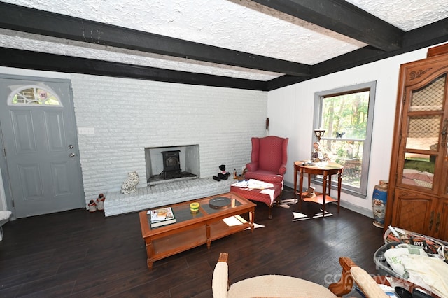 living room featuring beamed ceiling, dark wood-type flooring, brick wall, and a textured ceiling