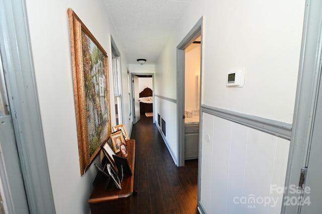 hall with a textured ceiling and dark hardwood / wood-style flooring