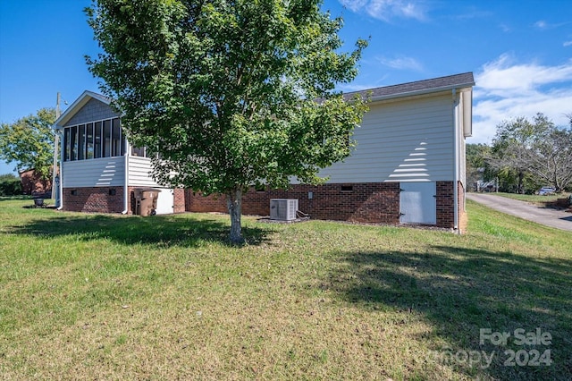 view of side of property featuring cooling unit, a sunroom, and a yard