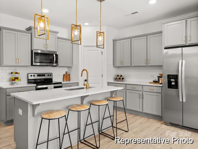 kitchen featuring appliances with stainless steel finishes, gray cabinets, sink, and light hardwood / wood-style flooring