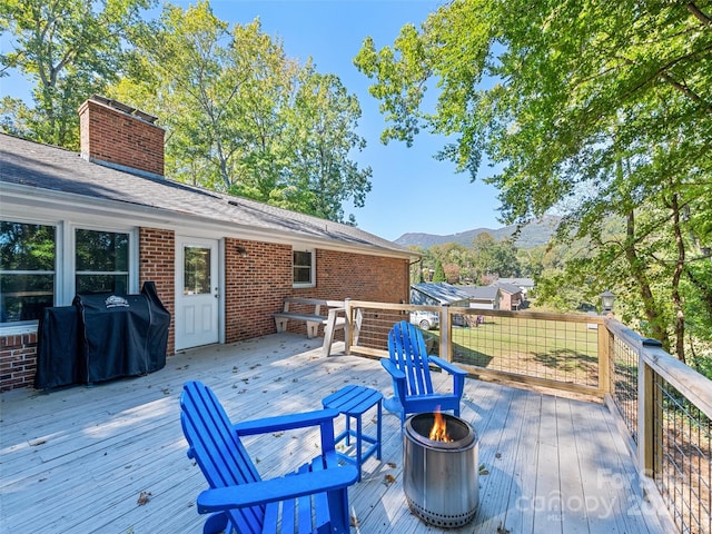 wooden terrace featuring a mountain view, a grill, and an outdoor fire pit