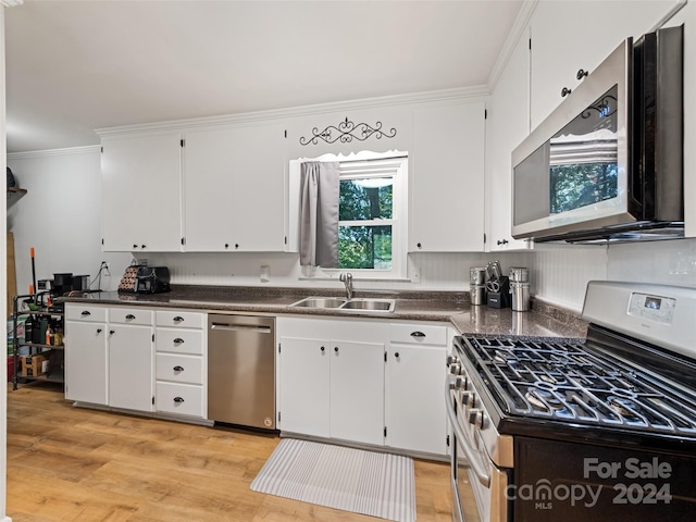 kitchen with light wood-type flooring, sink, ornamental molding, white cabinetry, and appliances with stainless steel finishes