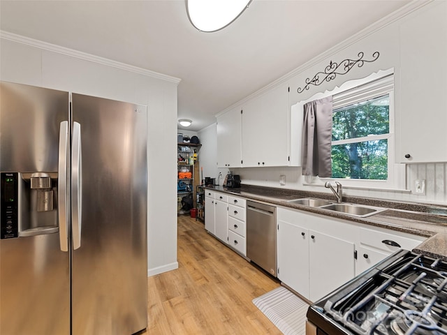 kitchen with light wood-type flooring, sink, ornamental molding, white cabinetry, and appliances with stainless steel finishes