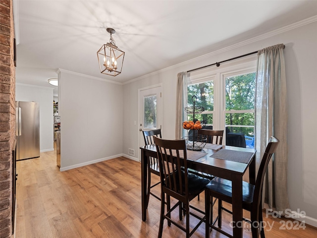 dining area with crown molding, an inviting chandelier, and light hardwood / wood-style floors