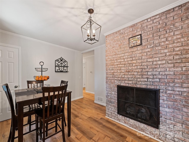 dining area with wood-type flooring, a fireplace, and crown molding