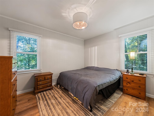 bedroom with ornamental molding, light wood-type flooring, and multiple windows