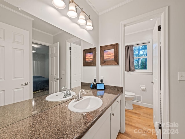 bathroom featuring crown molding, hardwood / wood-style flooring, vanity, and toilet