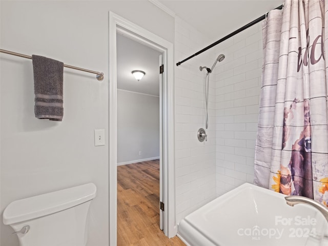 bathroom with hardwood / wood-style floors, toilet, crown molding, and tiled shower