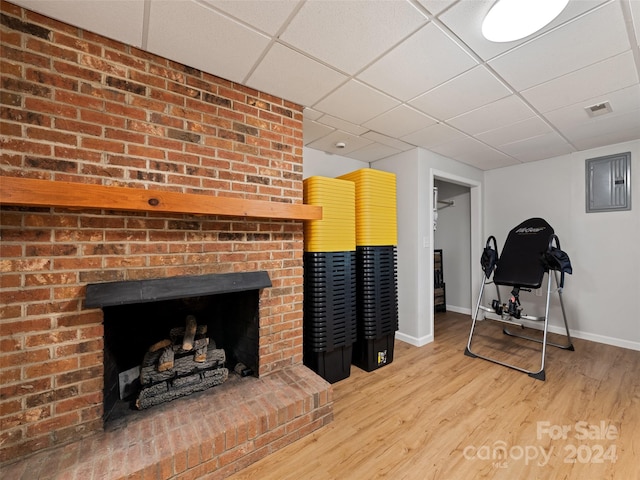 workout area featuring a drop ceiling, a fireplace, and hardwood / wood-style floors