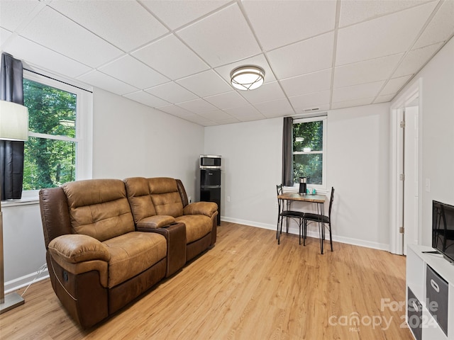 living room with a drop ceiling and light wood-type flooring