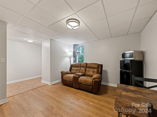 living room with a paneled ceiling and light wood-type flooring