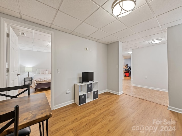 interior space with a drop ceiling and hardwood / wood-style floors