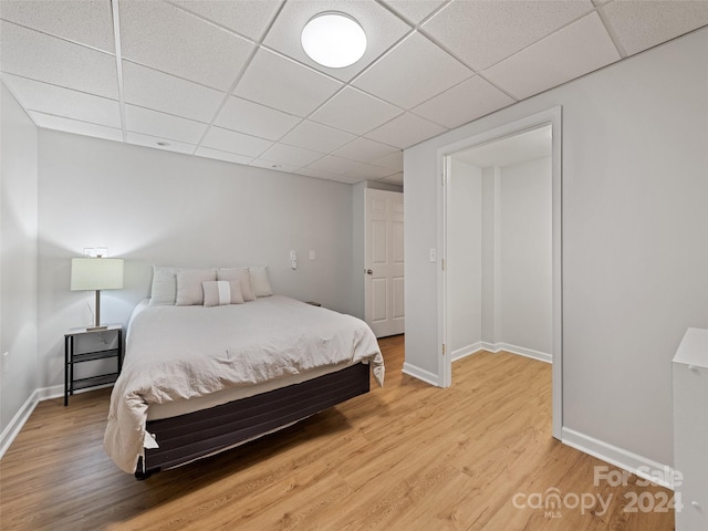 bedroom with a drop ceiling and wood-type flooring