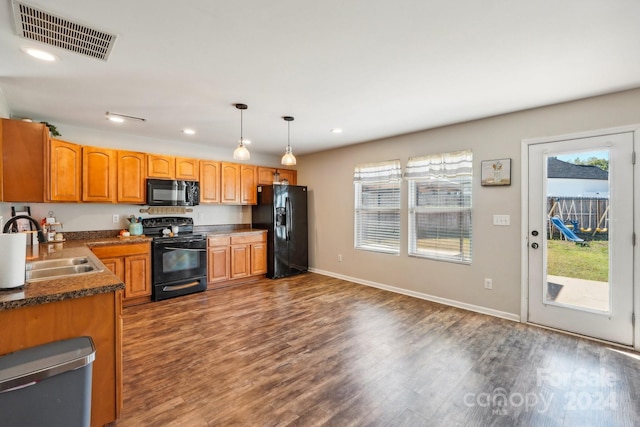 kitchen with black appliances, decorative light fixtures, sink, and dark hardwood / wood-style flooring